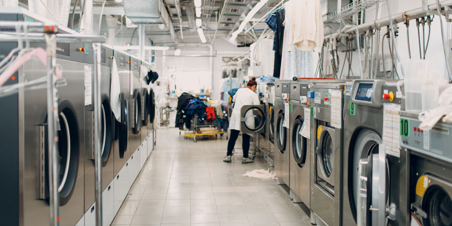Trabajadora lavandería industrial que sabe cómo ahorrar energía mediante la reducción del consumo